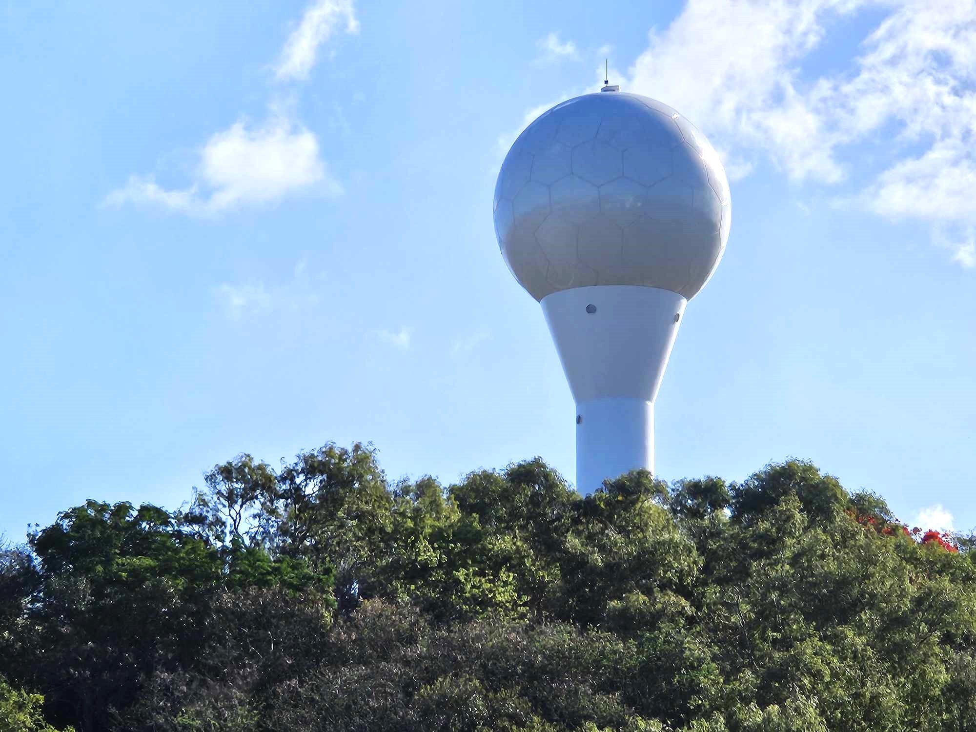 A weather radar with a blue sky and green trees.