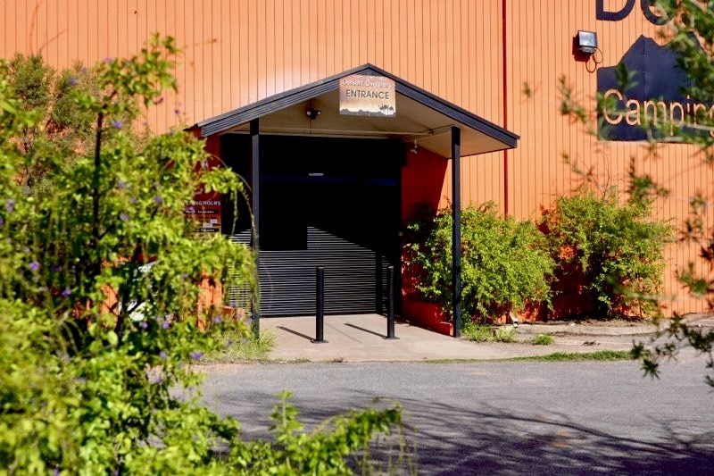 The exterior of a rust-coloured warehouse with the black roller door closed over the entrance.