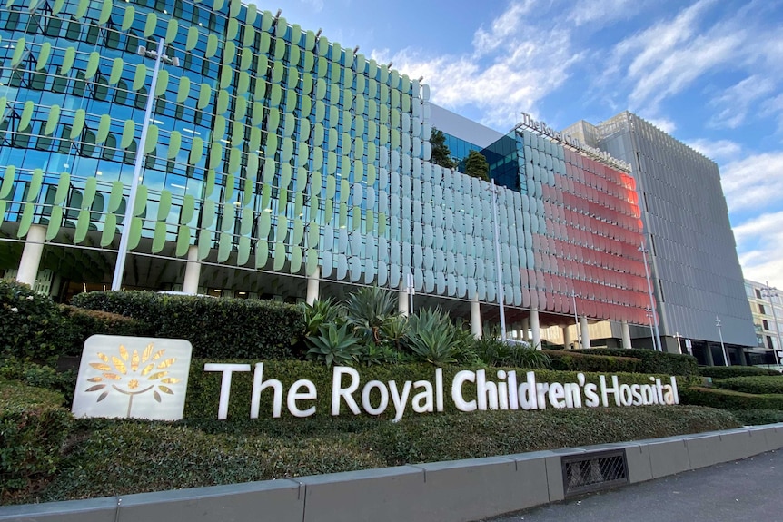 A sign saying "The Royal Children's Hospital" sits in a garden in front of one of the facility's large, colourful buildings.