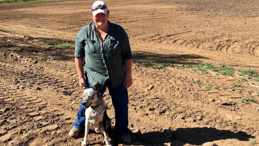 Ellie Boyd stands with her dog in a fallow field previously damaged by Cyclone Debbie.