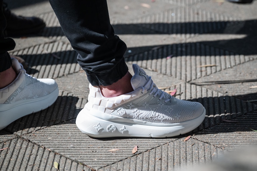 A close up white Louis Vuitton sneakers a man is wearing.