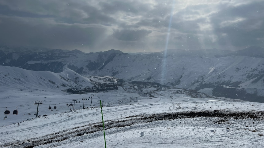 Snow on mountains with a ski chairlift.