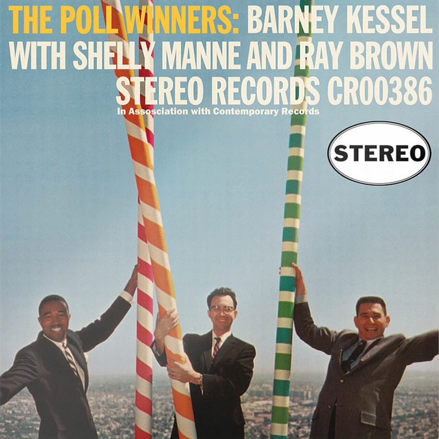 L to R: Ray Brown, Barney Kessel and SHelley Manne standing in-front of some coloured poles in L.A.