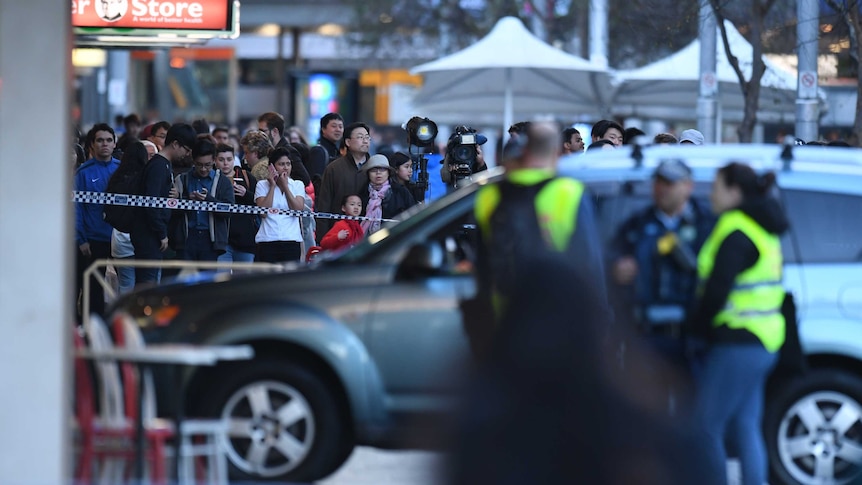 Members of the public watch NSW Police at the scene of a car accident in Chatswood