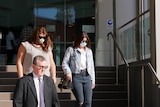 Two women and a man leaving a building