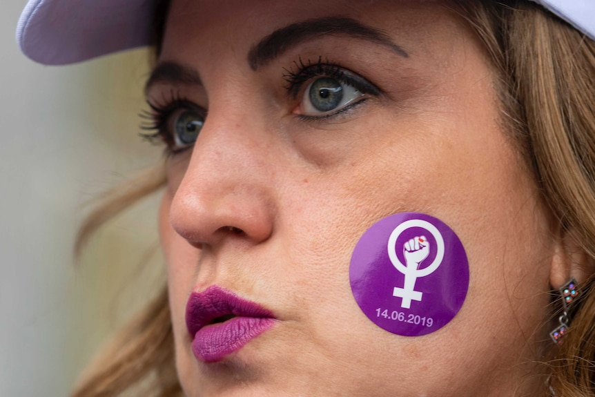 A blonde woman with a purple sticker on her cheek.