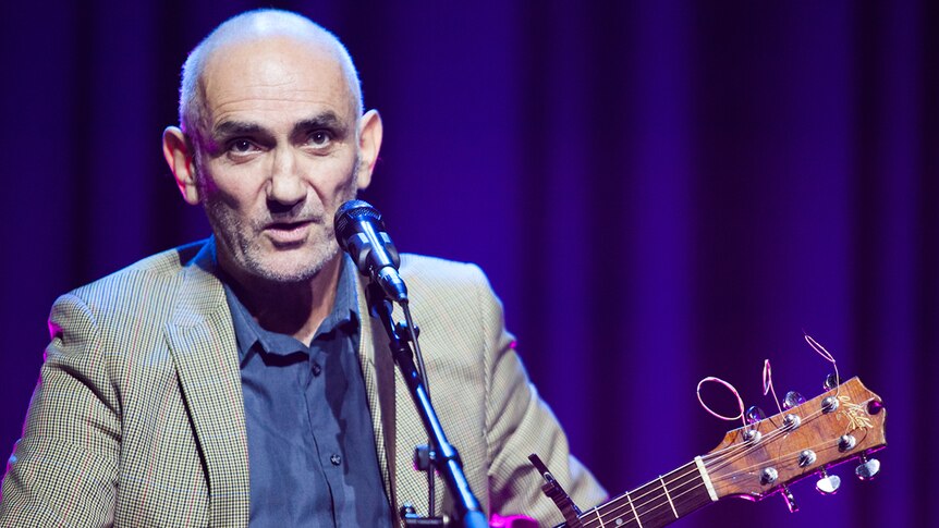 Paul Kelly on stage with a guitar at ABC Melbourne's Studio 31.
