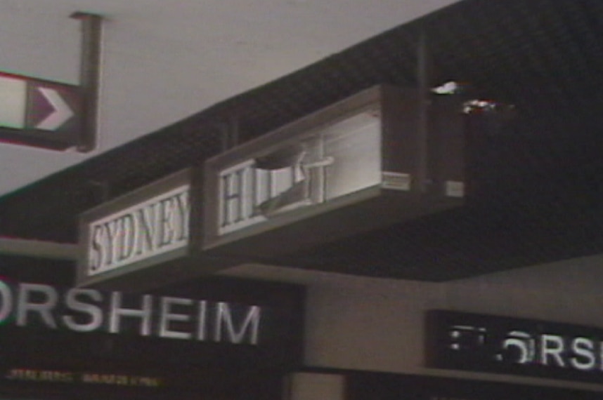 A smashed sign hanging from a roof.