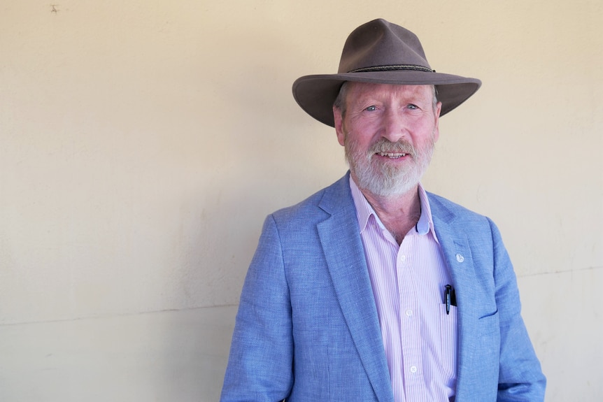 A man with  a broad-brimmed hat looking at the camera.