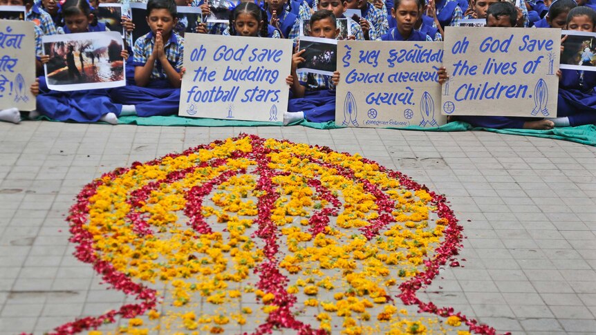 Siswa di India berdoa di depan karangan bunga yang melambangkan anak-anak yang terjebak di dalam gua di Thailand
