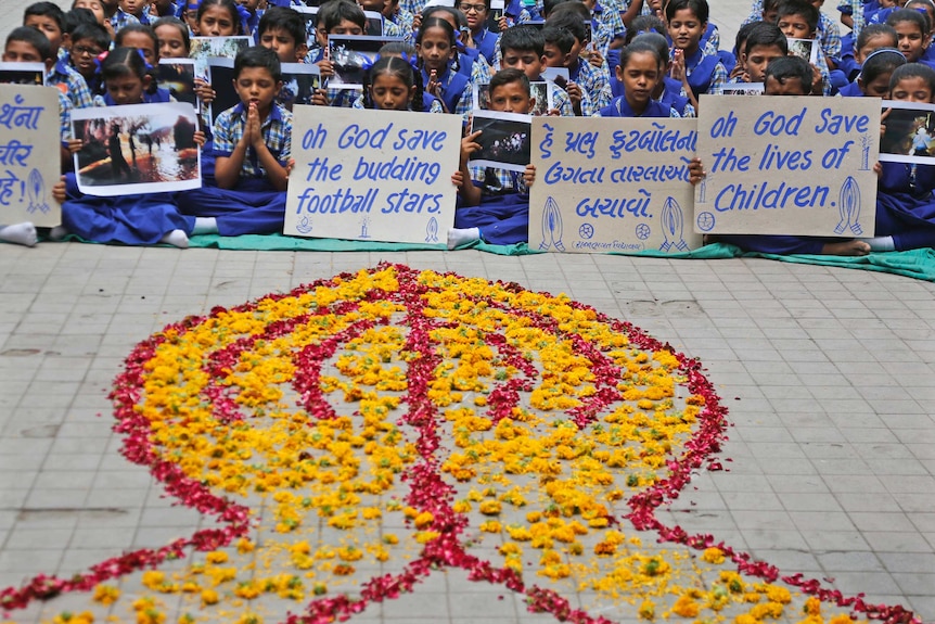 Indian students pray in front of mural for Thai cave boys