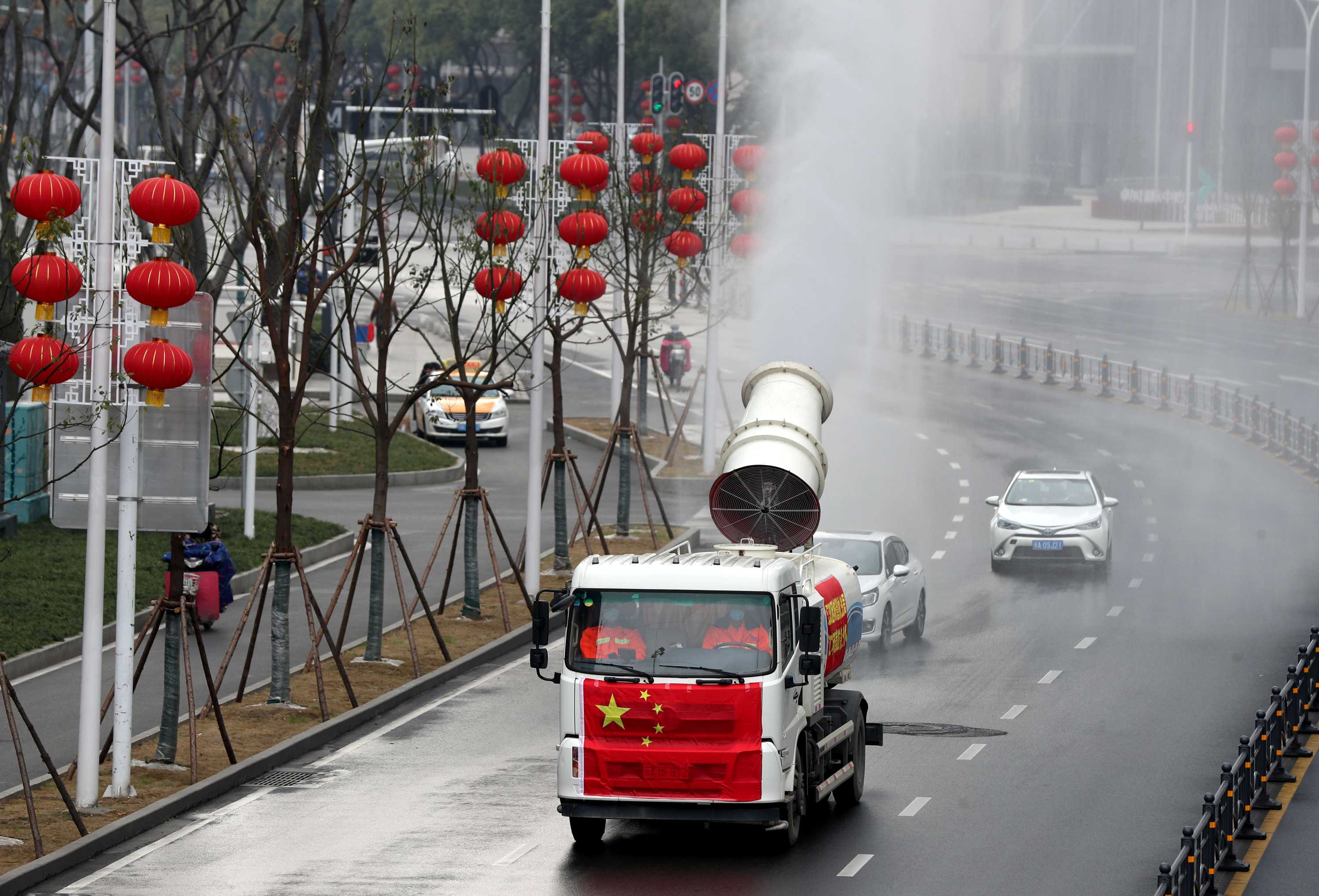 A truck painted with the Chinese national flag fumigate a street decorated with red Chinese lantens.