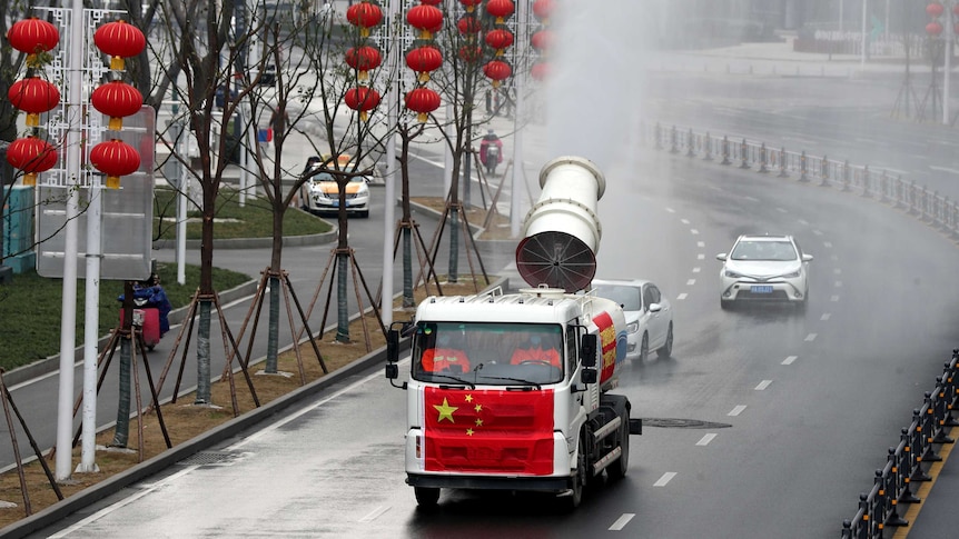 A truck painted with the Chinese national flag fumigate a street decorated with red Chinese lantens.