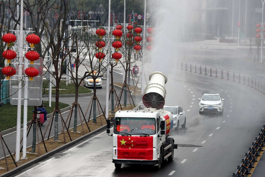 A truck painted with the Chinese national flag fumigate a street decorated with red Chinese lantens.