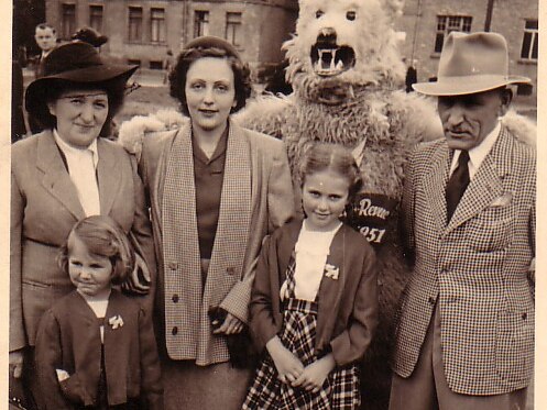 Two women, a person in bear costume and a man with two young girls standing in front of them.
