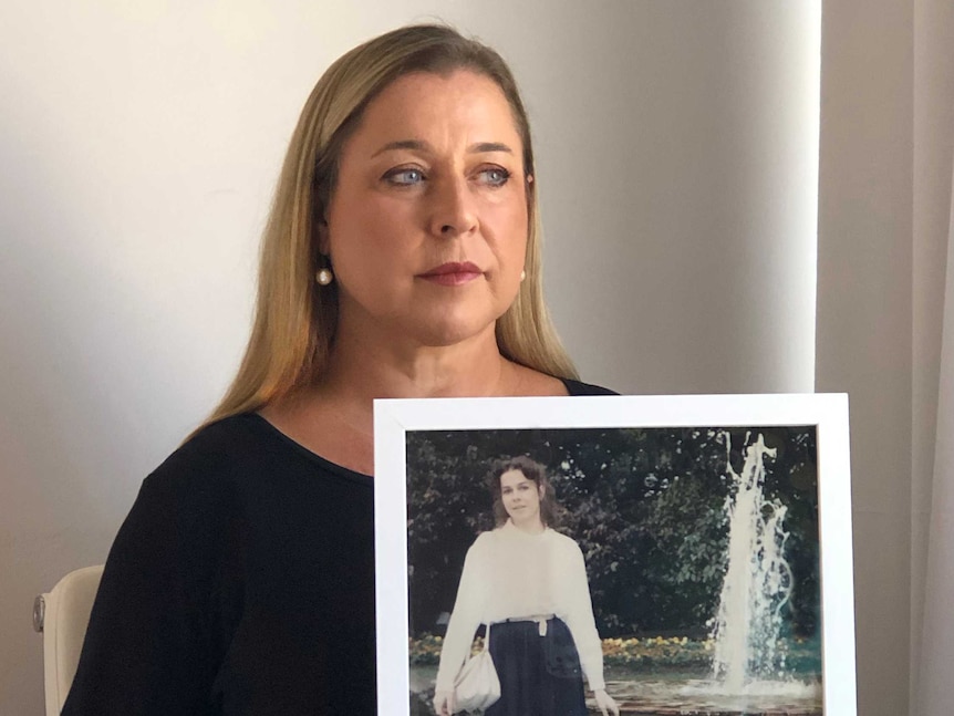 Eileen Culleton sits at a table holding a photo of her murdered sister Anne-Marie.