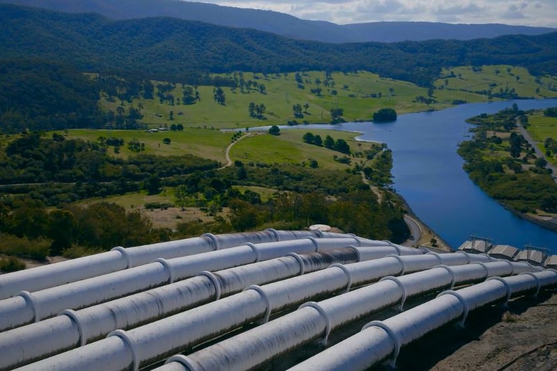 Six water pipes run downhill towards a dam.