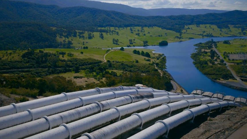 Six water pipes run downhill towards a dam.