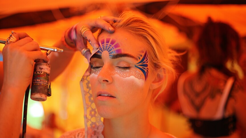 A woman gets her face painted at Byron Falls Festival