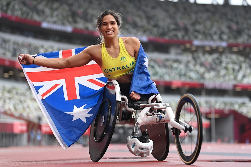 Medallista de oro paralímpico sonriendo con la bandera de Australia después de ganar el oro en el maratón femenino