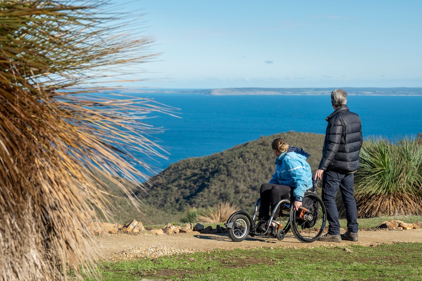 Yvette Eglinton riding along a walking trail near the beach in a wheelchair.