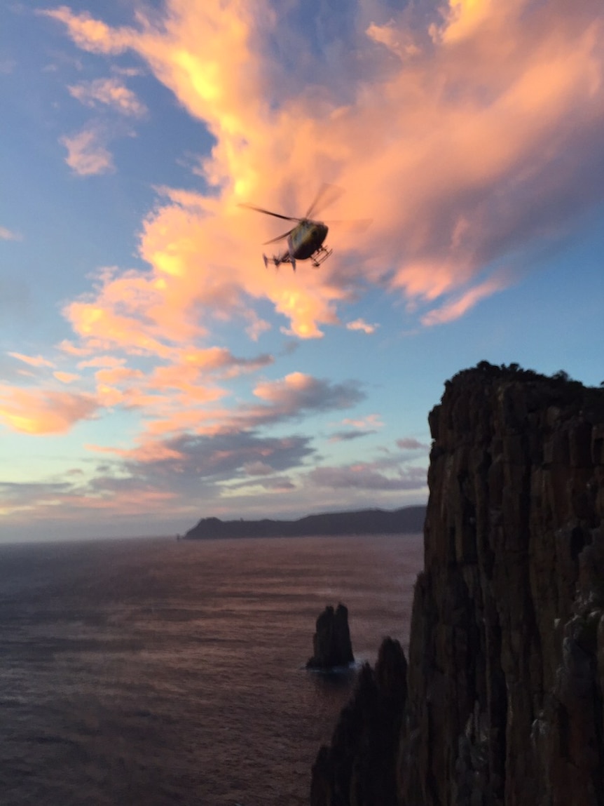 A rescue helicopter hovers at the Totem Pole in Tasmania.