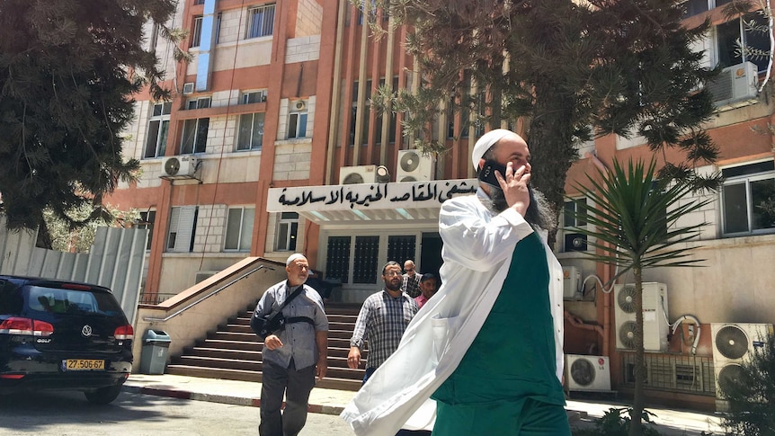 Staff, patients and visitors walk out of the Makassad Hospital in East Jerusalem.