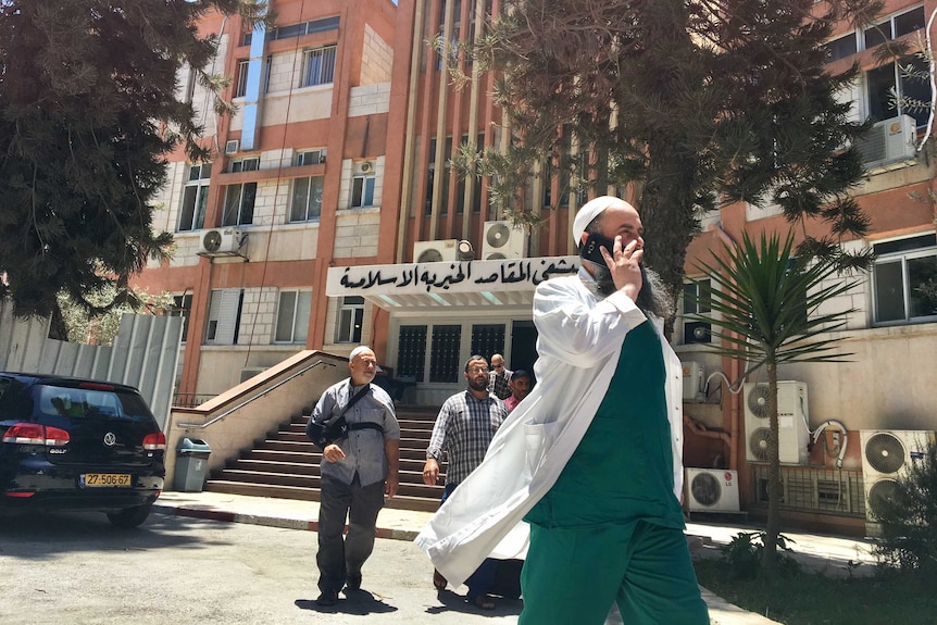 Staff, patients and visitors walk out of the Makassad Hospital in East Jerusalem.