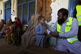 A volunteer hands medicine to a boy in Pakistan