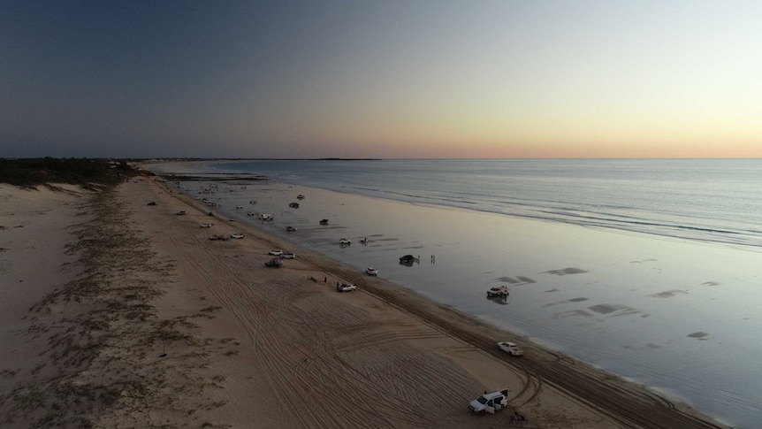 An aerial shot of a wide northern Australian beach at dusk.