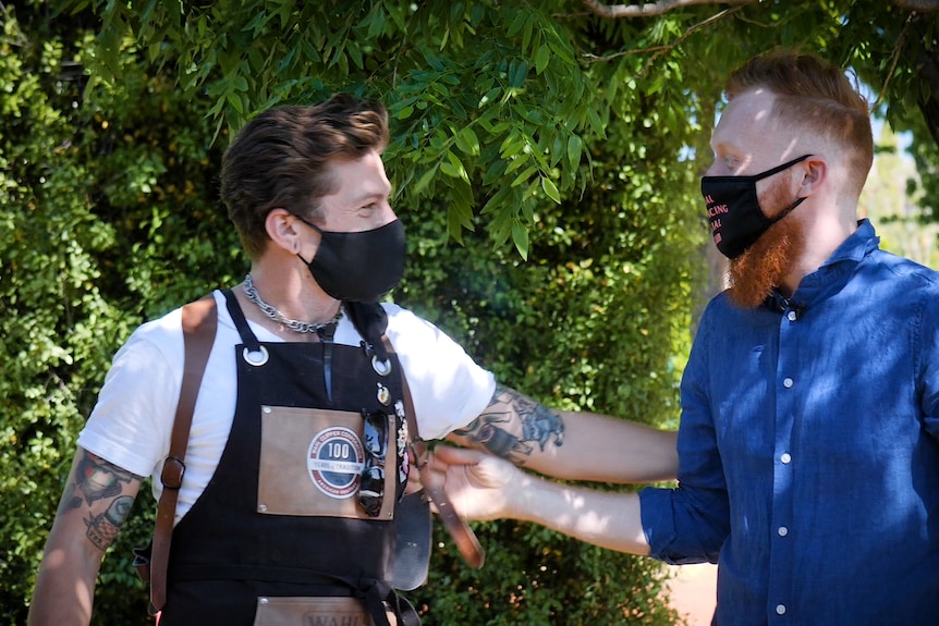 Sam and Brent smile at each other, wearing face masks.