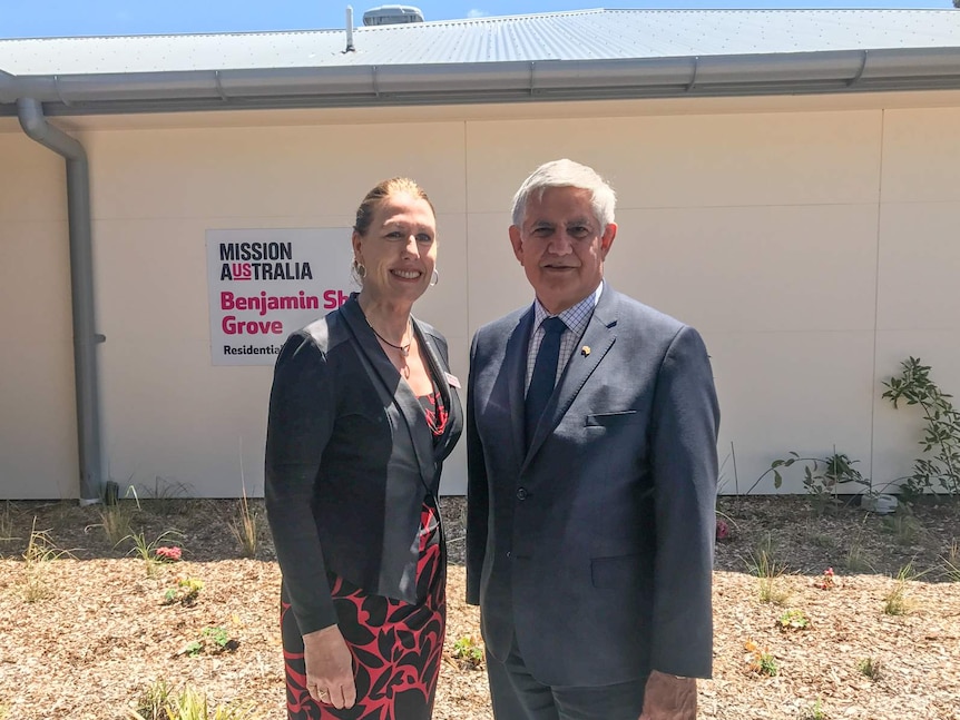 Woman and man standing in front of Mission Australia sign.