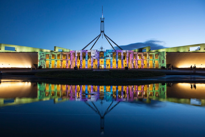Parliament House lit up with different-coloured words during the Enlighten festival.