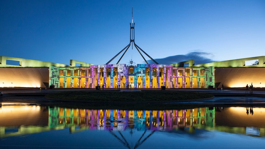 Parliament House lit up with different-coloured words during the Enlighten festival.