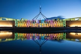 Parliament House lit up with different-coloured words during the Enlighten festival.