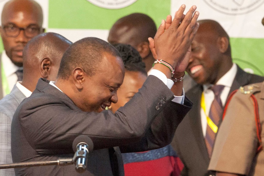Uhuru Kenyatta claps his hands and smiles.