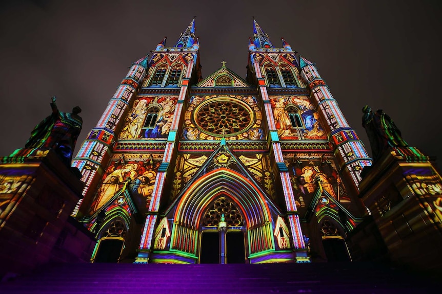 a church at night being illuminated artistic lighting showing religious figures