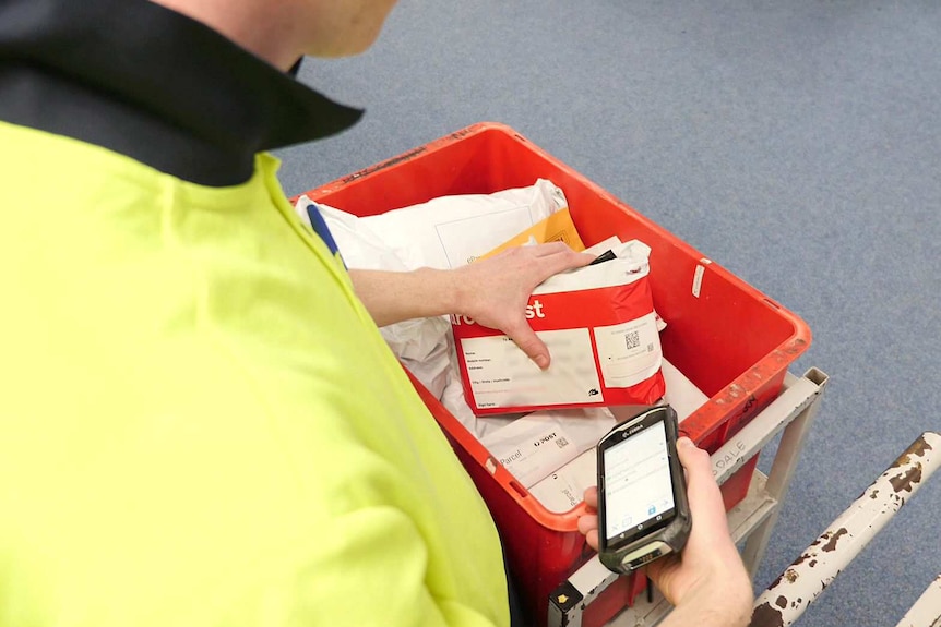 An Australian Post worker scans the code on a package.