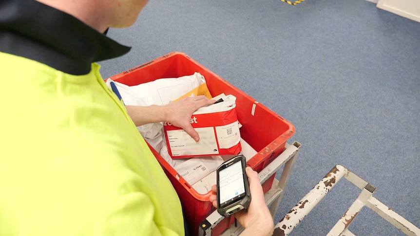 An Australian Post worker scans the code on a package.