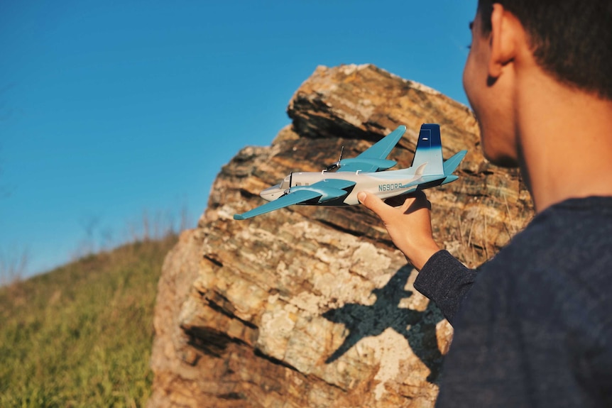 Unidentified boy plays outside with a plane.