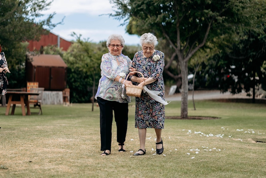 Two grandmothers spread flowers at a wedding.