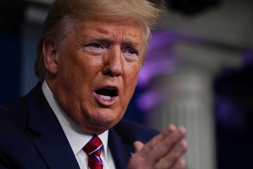 Donald Trump wearing a suit gestures with his hand as he speaks.