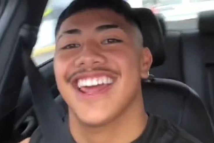 a young male sitting in a car smiling at the camera