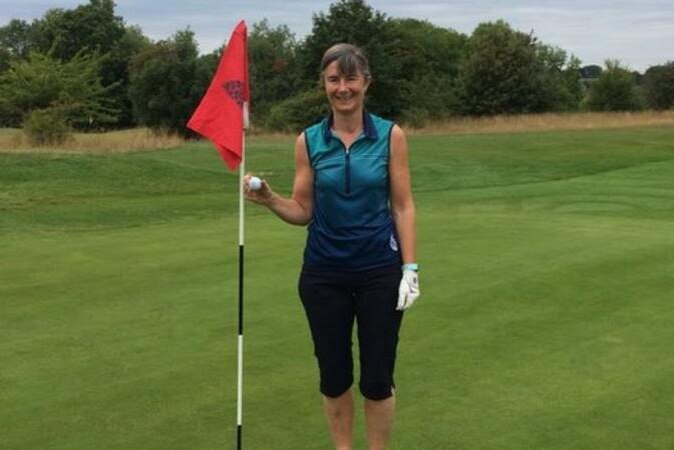 A golfer holds a ball and a flag