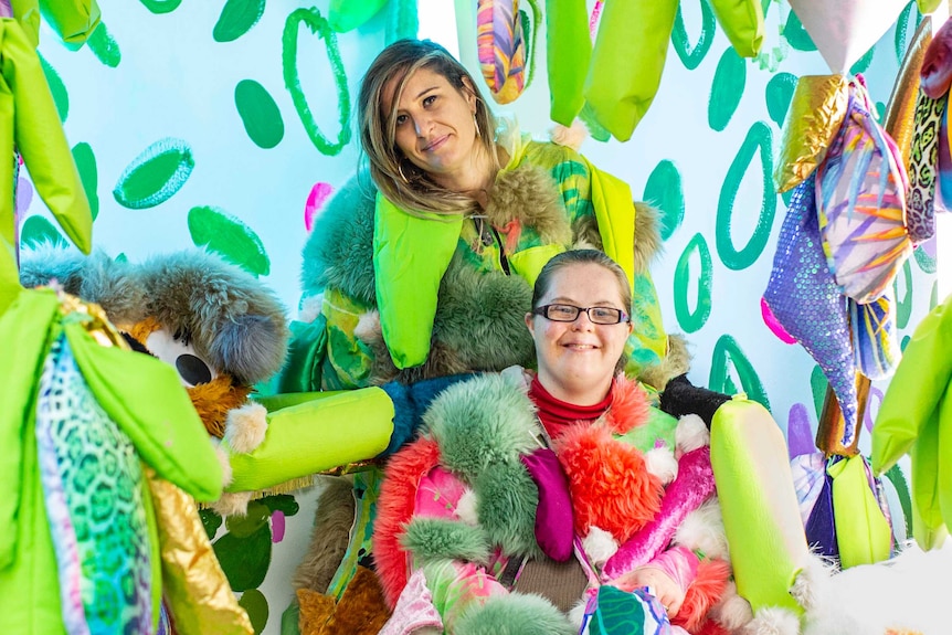 The two artists, wearing multi-coloured furry costumes, stand in their psychedelically coloured installation.