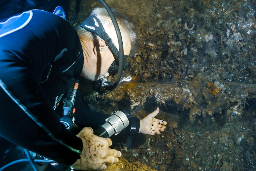 A diver touches a glob of oil in a sunken shipwreck. 