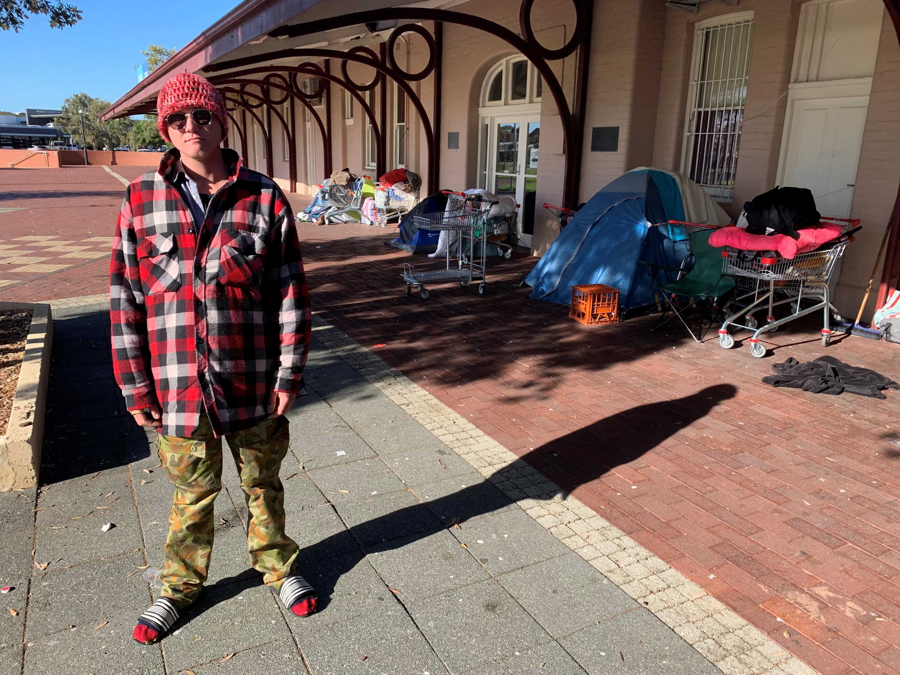 Jack is homeless and is standing in front of the tent where he sleeps