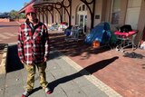 Jack is homeless and is standing in front of the tent where he sleeps.