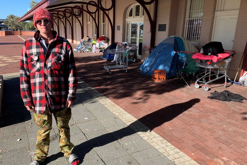 Jack is homeless and is standing in front of the tent where he sleeps