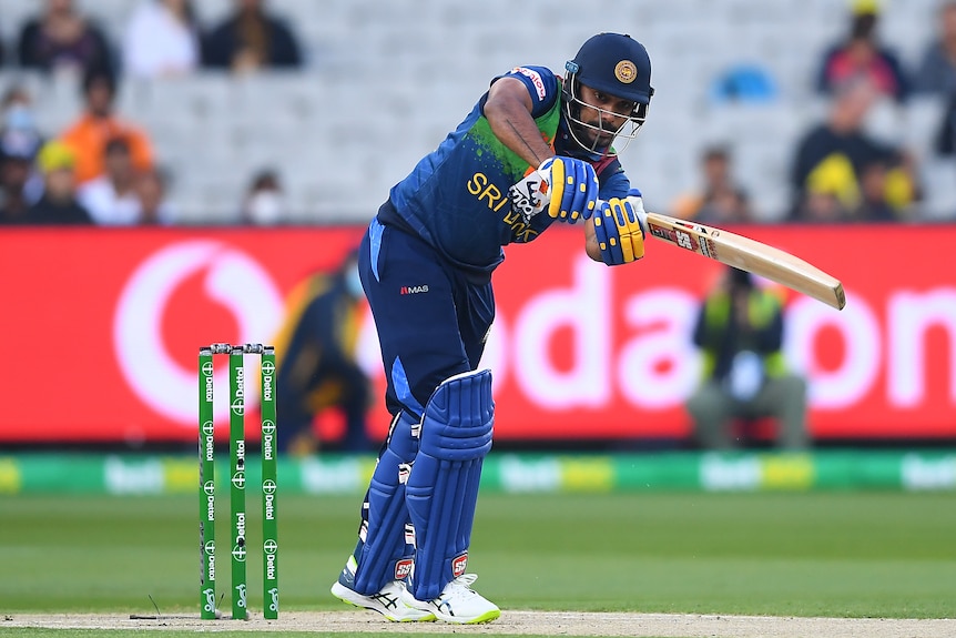 a cricket player on the pitch hitting a ball